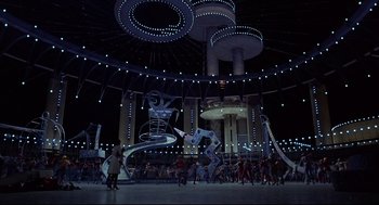 Movie still from “The Wiz” (1978), directed by Sidney Lumet – A group of people standing in front of a building at night; Extreme Wide shot, High angle