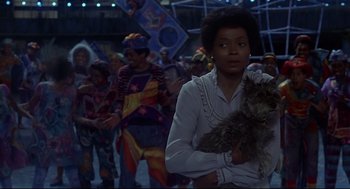 Movie still from “The Wiz” (1978), directed by Sidney Lumet – A woman holding a small dog in front of a group of people; Medium shot, Low angle