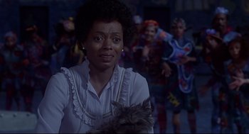 Movie still from “The Wiz” (1978), directed by Sidney Lumet – A woman holding a dog in front of a group of people; Close Up shot, Over the shoulder angle