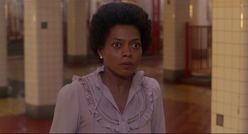 Movie still from “The Wiz” (1978), directed by Sidney Lumet – A woman in a pink shirt is standing in a room; Close Up shot, Over the shoulder angle