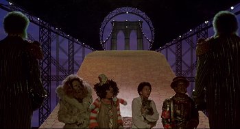 Movie still from “The Wiz” (1978), directed by Sidney Lumet – A group of people standing next to each other in front of a bridge; Wide shot, Low angle