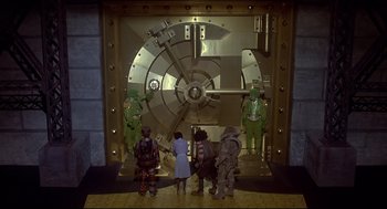 Movie still from “The Wiz” (1978), directed by Sidney Lumet – A group of people standing in front of a large metal door; Wide shot, High angle