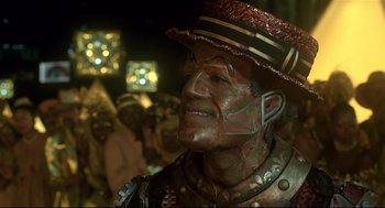Movie still from “The Wiz” (1978), directed by Sidney Lumet – A man with a hat and face paint in front of a group of people; Close Up shot, Low angle