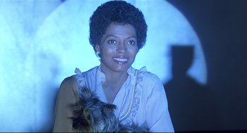 Movie still from “The Wiz” (1978), directed by Sidney Lumet – A woman holding a dog in her arms and smiling for the camera; Close Up shot, Low angle