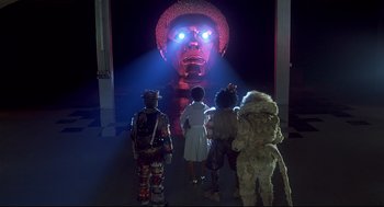 Movie still from “The Wiz” (1978), directed by Sidney Lumet – A group of people standing in front of a giant mask; Extreme Wide shot, Low angle