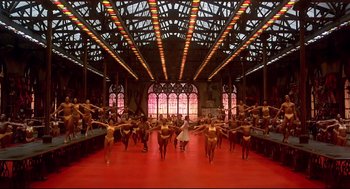Movie still from “The Wiz” (1978), directed by Sidney Lumet – A group of people standing on a red floor in front of stained glass windows; Extreme Wide shot, High angle