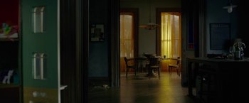 Movie still from “The Woman in the Window” (2021), directed by Joe Wright – A dining room table and chairs in a room with two windows; Wide shot, High angle