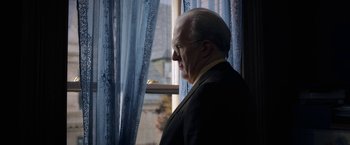 Movie still from “The Woman in the Window” (2021), directed by Joe Wright – An older man looking out of a window; Medium shot, Low angle