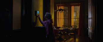 Movie still from “The Woman in the Window” (2021), directed by Joe Wright – A woman is adjusting the temperature on a thermostat; Wide shot, Over the shoulder angle