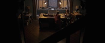 Movie still from “The Woman in the Window” (2021), directed by Joe Wright – Two people sitting at a table in a kitchen; Wide shot, High angle