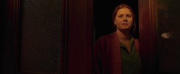 Movie still from “The Woman in the Window” (2021), directed by Joe Wright – A woman standing in front of a mirror in a dark room; Close Up shot, Over the shoulder angle