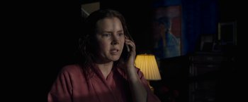 Movie still from “The Woman in the Window” (2021), directed by Joe Wright – A woman talking on a cell phone in the dark; Medium shot, Low angle