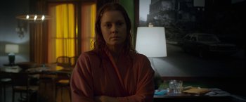 Movie still from “The Woman in the Window” (2021), directed by Joe Wright – A woman with long red hair is posing for a picture; Medium shot, Over the shoulder angle