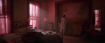 Movie still from “The Woman in the Window” (2021), directed by Joe Wright – A person standing in a bedroom next to a bed; Wide shot, Low angle