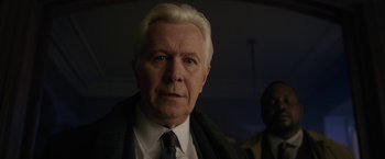 Movie still from “The Woman in the Window” (2021), directed by Joe Wright – An older man wearing a suit and a tie; Close Up shot, Over the shoulder angle
