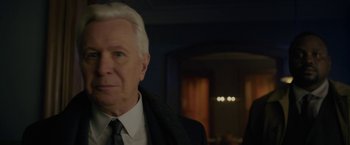Movie still from “The Woman in the Window” (2021), directed by Joe Wright – An older man in a suit and tie in front of a doorway; Close Up shot, Over the shoulder angle