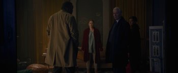 Movie still from “The Woman in the Window” (2021), directed by Joe Wright – A woman standing next to two men in a room; Wide shot, Over the shoulder angle