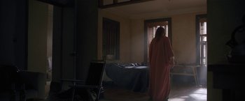 Movie still from “The Woman in the Window” (2021), directed by Joe Wright – A woman standing in front of a bed in a room; Wide shot, Over the shoulder angle