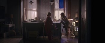 Movie still from “The Woman in the Window” (2021), directed by Joe Wright – Two people sitting at a table in front of a window; Wide shot, Over the shoulder angle