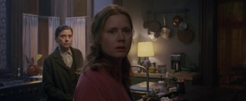 Movie still from “The Woman in the Window” (2021), directed by Joe Wright – A woman standing in front of a kitchen counter; Medium shot, Over the shoulder angle