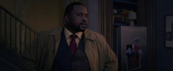 Movie still from “The Woman in the Window” (2021), directed by Joe Wright – A man wearing a jacket and a tie in a room; Medium shot, Over the shoulder angle