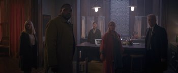 Movie still from “The Woman in the Window” (2021), directed by Joe Wright – A group of people standing around a table; Wide shot, Over the shoulder angle