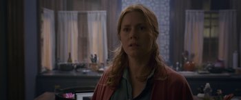 Movie still from “The Woman in the Window” (2021), directed by Joe Wright – A woman with long blonde hair standing in front of a window; Medium shot, Over the shoulder angle