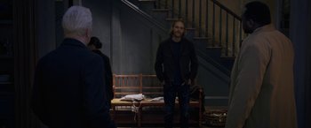 Movie still from “The Woman in the Window” (2021), directed by Joe Wright – A man standing in front of a bench in a room; Medium shot, Over the shoulder angle