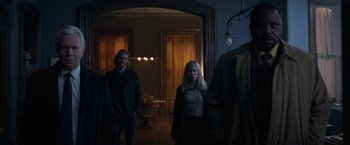 Movie still from “The Woman in the Window” (2021), directed by Joe Wright – A group of people standing in a living room; Medium shot, Low angle