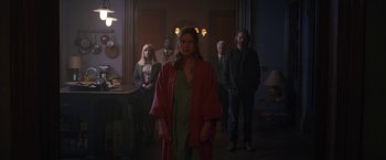 Movie still from “The Woman in the Window” (2021), directed by Joe Wright – A group of people standing in a dark room; Wide shot, Over the shoulder angle