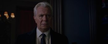 Movie still from “The Woman in the Window” (2021), directed by Joe Wright – An older man wearing a suit and tie; Close Up shot, Over the shoulder angle