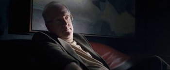Movie still from “The Woman in the Window” (2021), directed by Joe Wright – An older man sitting in a chair wearing glasses; Close Up shot, Low angle