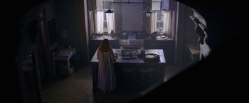 Movie still from “The Woman in the Window” (2021), directed by Joe Wright – A woman standing in front of an island in a kitchen; Wide shot, High angle