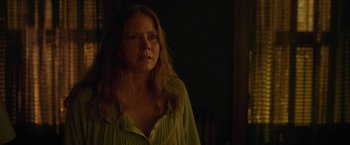 Movie still from “The Woman in the Window” (2021), directed by Joe Wright – A woman standing in the dark with her head turned to the side; Close Up shot, Over the shoulder angle