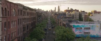 Movie still from “The Woman in the Window” (2021), directed by Joe Wright – An aerial view of a city street at sunset; Extreme Wide shot, High angle