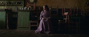 Movie still from “The Wonder” (2022), directed by Sebastián Lelio – A woman in a purple dress sitting on a chair; Wide shot, Low angle