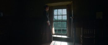 Movie still from “The Wonder” (2022), directed by Sebastián Lelio – A woman standing in front of an open window; Wide shot, Low angle