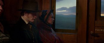 Movie still from “The Wonder” (2022), directed by Sebastián Lelio – A man and a woman sitting next to each other on a train; Medium shot, Low angle