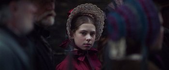 Movie still from “The Wonder” (2022), directed by Sebastián Lelio – A young girl wearing a red dress and a lace hat; Close Up shot, Over the shoulder angle