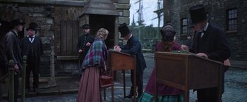 Movie still from “The Wonder” (2022), directed by Sebastián Lelio – A group of people standing next to each other on a street; Wide shot, High angle