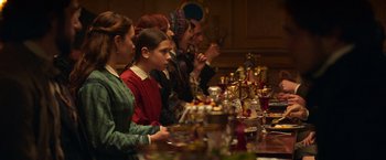 Movie still from “The Wonder” (2022), directed by Sebastián Lelio – A group of people sitting at a table with food; Medium shot, Over the shoulder angle
