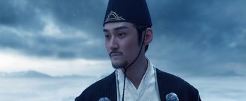 Movie still from “The Yin-Yang Master: Dream of Eternity” (2020), directed by Jingming Guo – A man with a beard wearing a hat and a black jacket; Close Up shot, Low angle