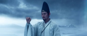 Movie still from “The Yin-Yang Master: Dream of Eternity” (2020), directed by Jingming Guo – A man wearing a hat standing in front of a cloudy sky; Medium shot, Low angle
