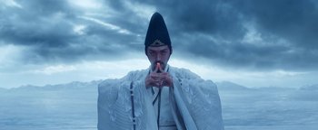 Movie still from “The Yin-Yang Master: Dream of Eternity” (2020), directed by Jingming Guo – A man in a white robe and a black hat is holding his hands to his mouth; Medium shot, Low angle