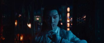 Movie still from “The Yin-Yang Master: Dream of Eternity” (2020), directed by Jingming Guo – A young man in traditional chinese garb is holding his finger to his lips; Close Up shot, Over the shoulder angle