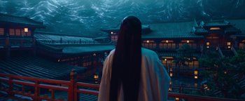 Movie still from “The Yin-Yang Master: Dream of Eternity” (2020), directed by Jingming Guo – A person with long black hair standing in front of a building; Medium shot, Over the shoulder angle