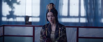 Movie still from “The Yin-Yang Master: Dream of Eternity” (2020), directed by Jingming Guo – A woman in a black and gold outfit holding a bouquet of flowers; Medium shot, Over the shoulder angle