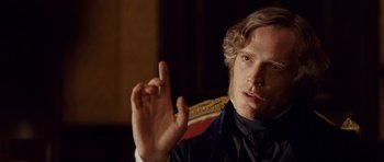 Movie still from “The Young Victoria” (2009), directed by Jean-Marc Vallée – A person sitting in a chair holding his hand up; Close Up shot, Over the shoulder angle