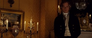 Movie still from “The Young Victoria” (2009), directed by Jean-Marc Vallée – A man standing in front of a lit candle holder; Medium shot, Over the shoulder angle