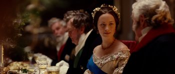 Movie still from “The Young Victoria” (2009), directed by Jean-Marc Vallée – A woman wearing a floral dress and a flower crown; Medium shot, Over the shoulder angle
